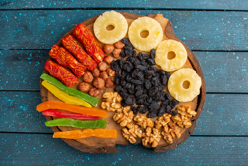 Variety of dry fruits and nuts on a platter with a blue background